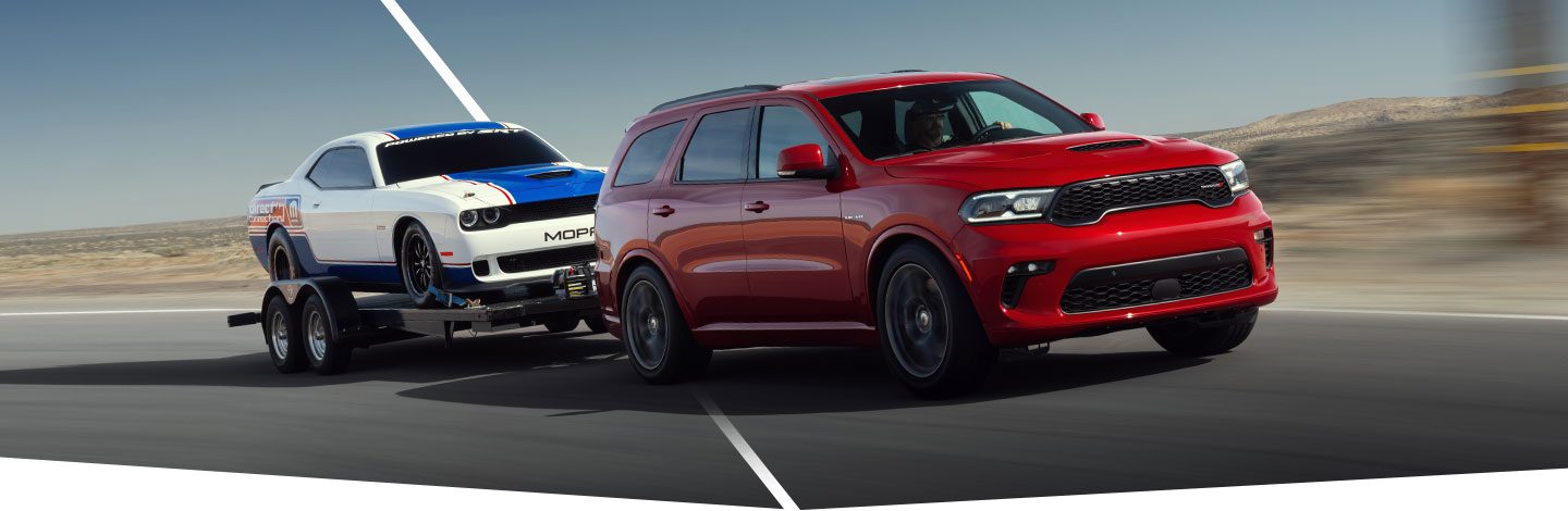 The 2021 Dodge Durango R/T towing a flatbed trailer with a Dodge Challenger on it.