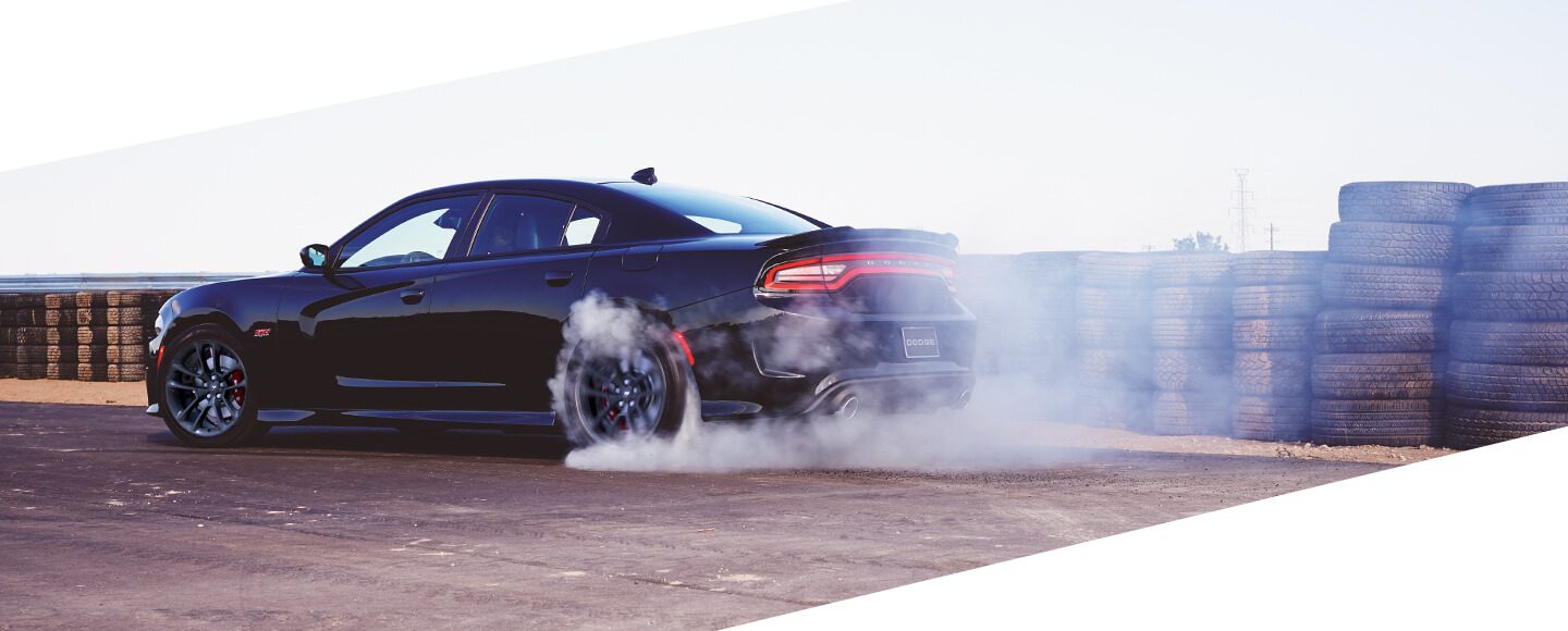 Smoke pouring from the rear tires of the 2020 Dodge Charger as it is driven on a racetrack.